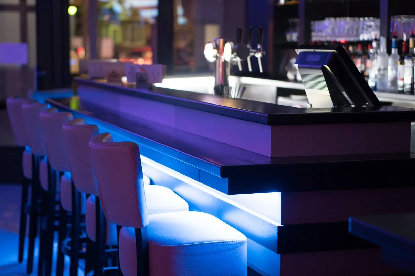 Le comptoir vu de côté, sa lumière bleue et ses tabourets