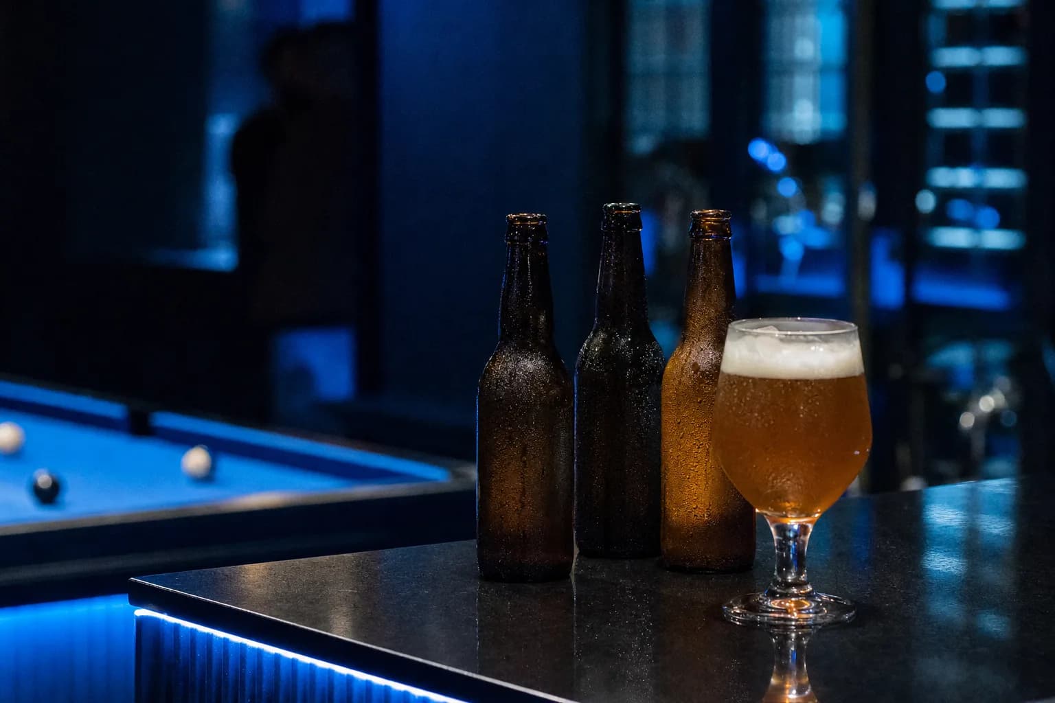 Des bières en bouteille et un verre servi sur le comptoir